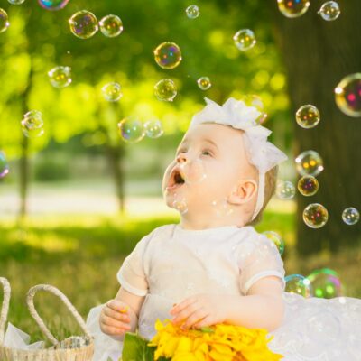 a baby sitting in the grass with bubbles in the air