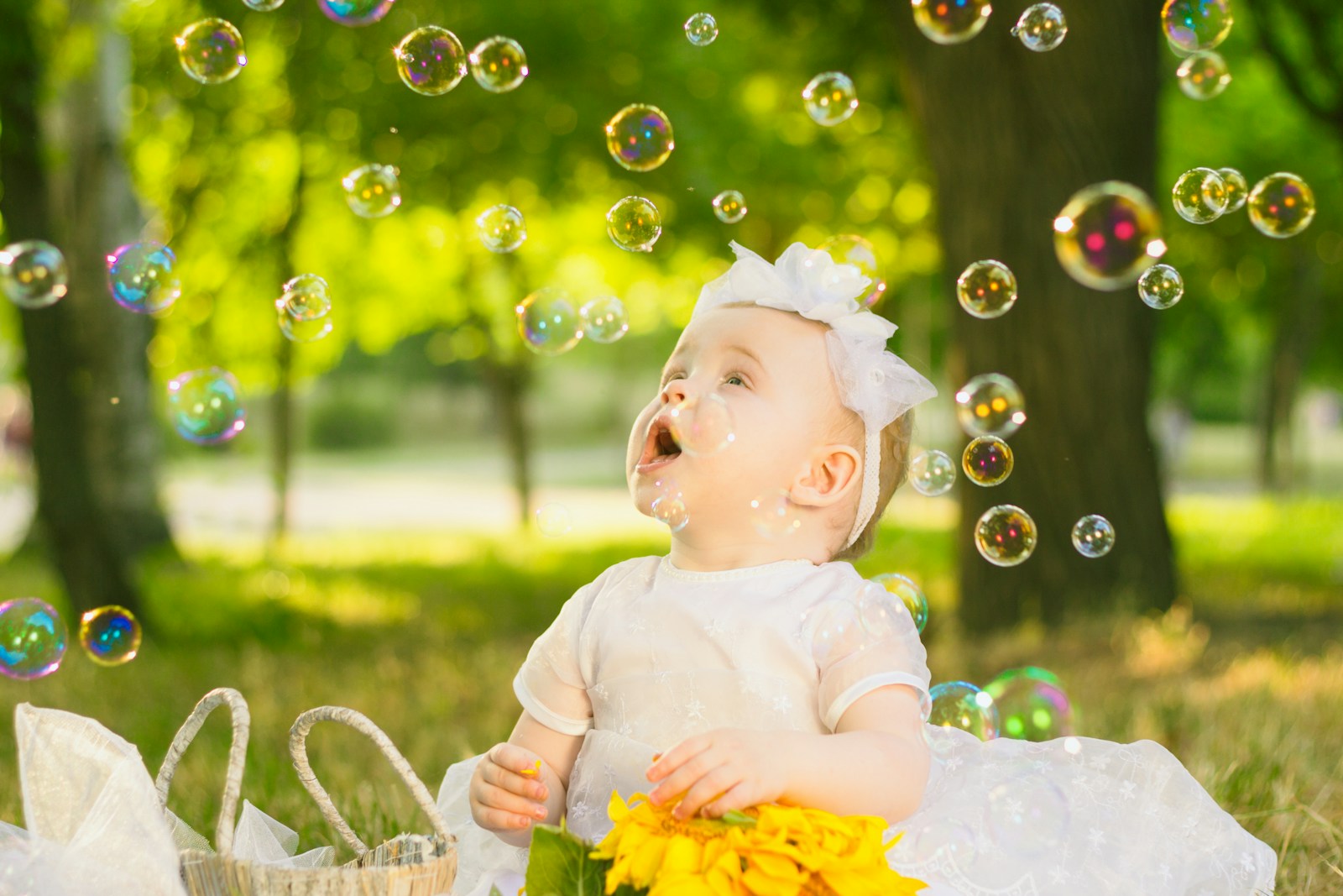 a baby sitting in the grass with bubbles in the air