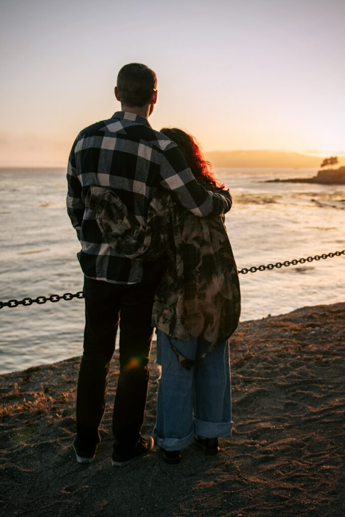 a man and woman kissing on a beach